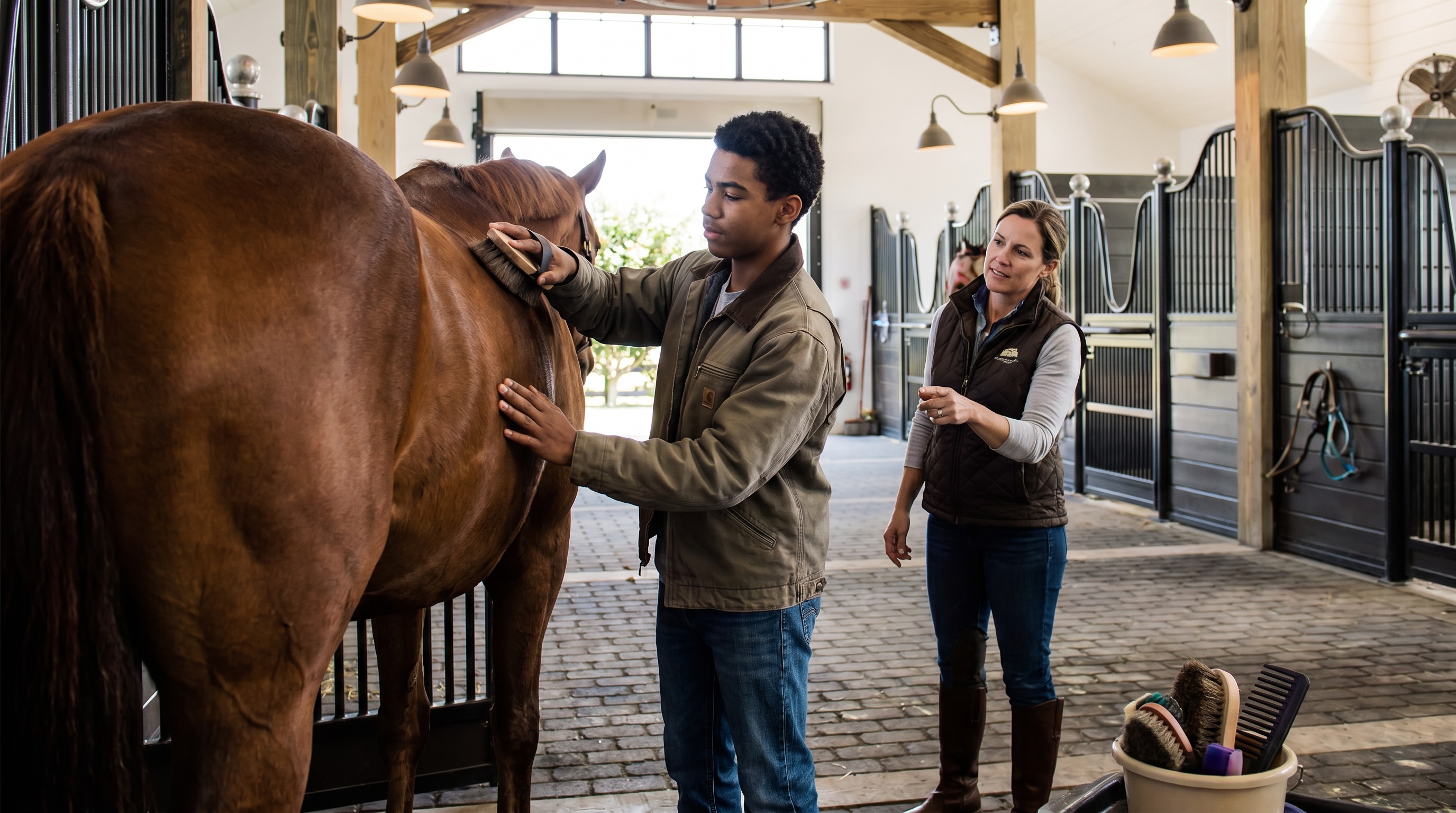 An EACPA student grooming a horse alongside an instructor